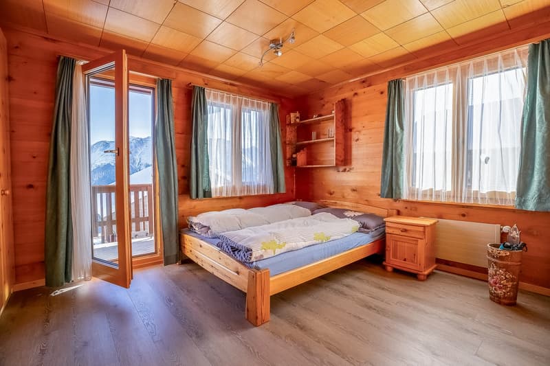 2 twin beds, wooden bed frame, window with balcony, curtains, radiator, wooden nightstand, wooden floor