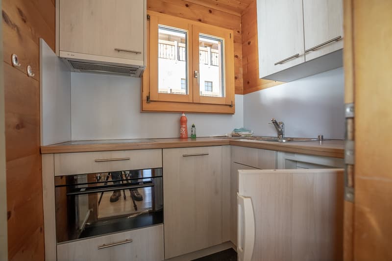 wooden cabinets, sink, countertop, oven, wooden flooring, window
