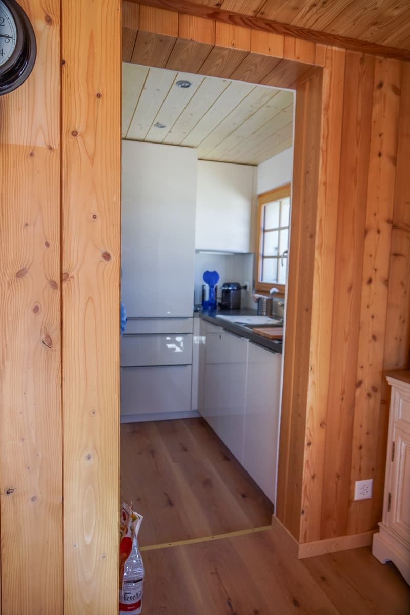 small kitchen with wooden wall, white cabinetry, granite counter, sink, dishwasher, refrigerator, power outlet