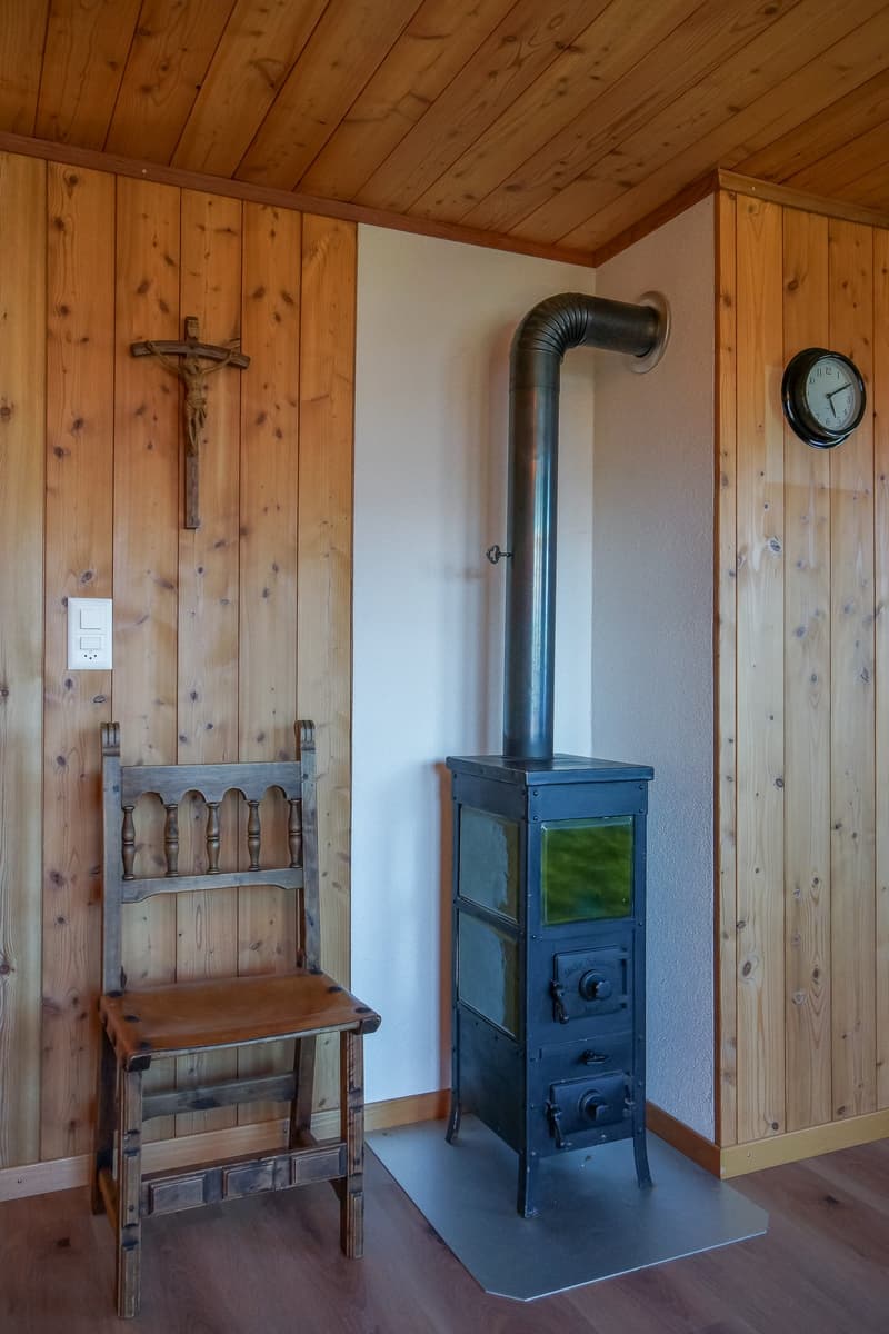 wooden walls, metal fireplace, clock, cross, chair, power outlet