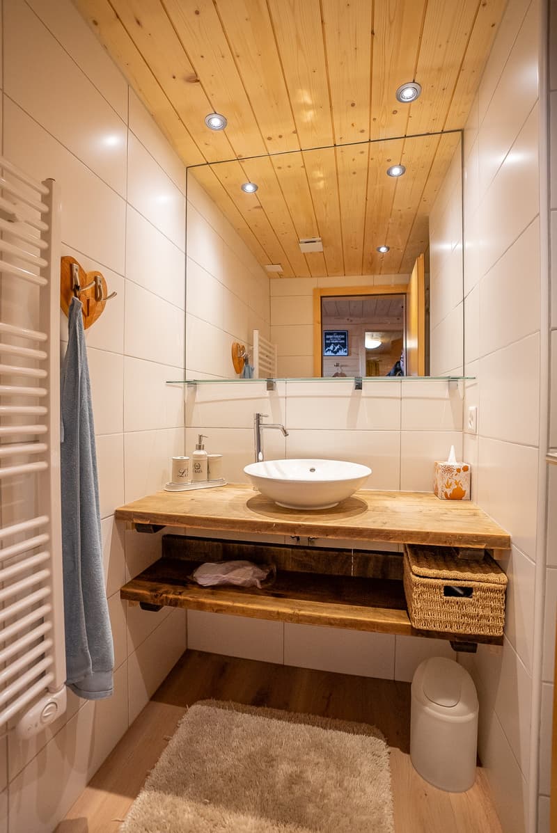 large mirror, wooden shelf, towel warmer, radiator, wooden ceiling, sink, faucet