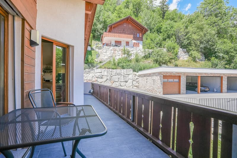 Mountain house, wooden exterior, stone wall, balcony with table, large garden, garage with car