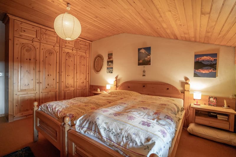 2 twin beds, wooden floor, wooden headboard, 2 nightstands, wooden wardrobe, lamps, and paintings on the wall.