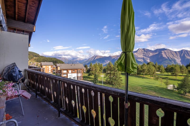 A balcony with a view of mountains and a golf course
