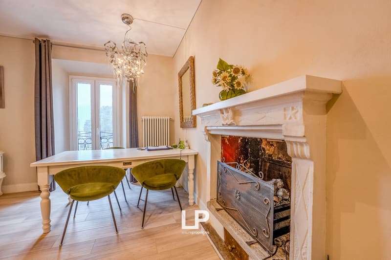 Dining room with a table, chairs, fireplace, chandelier, windows, and mirrors.