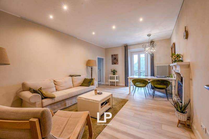 modern design, fireplace, white couch, green pillows, wooden table, chandelier, hardwood floors, dining chairs, table and chairs in dining area