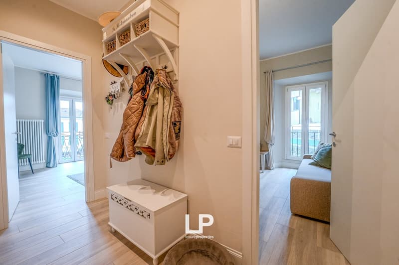A room with a coat rack, shelves, storage box, door, couch, balcony, and view