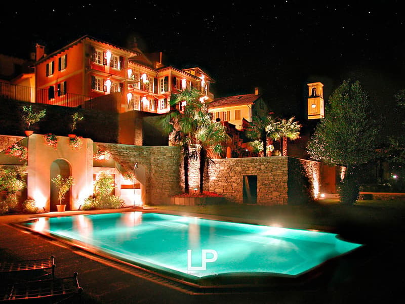 building with several windows, swimming pool, illuminated trees, plants, and flowers