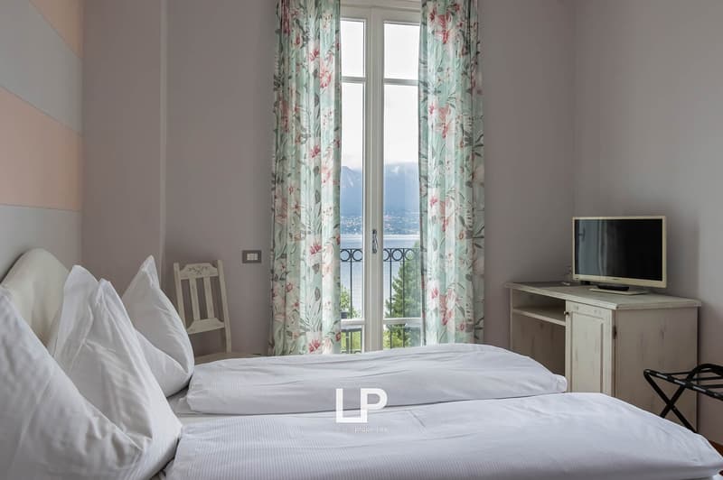twin beds, floral curtains, balcony with lake view, TV, desk, chair