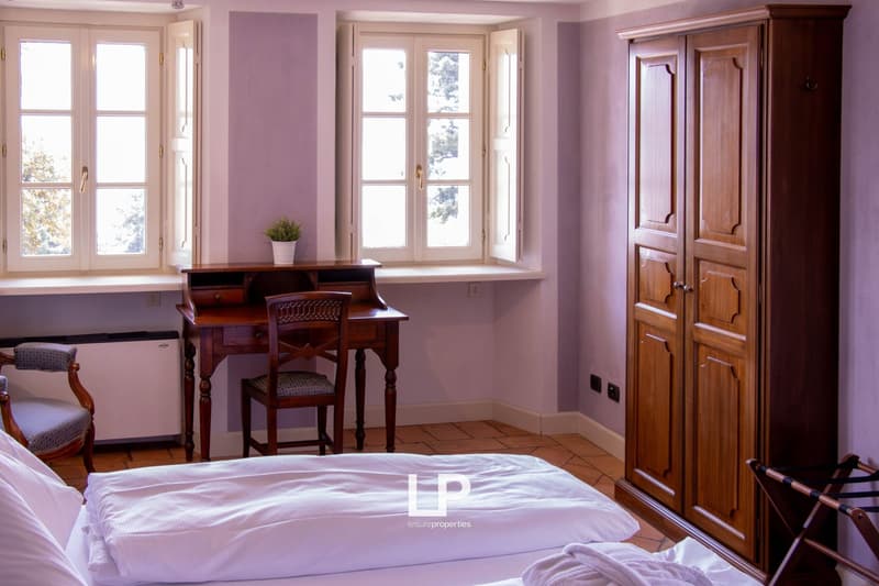 double bed, wooden desk with chair, wooden wardrobe, chair, radiator, windows, wooden floor, plants