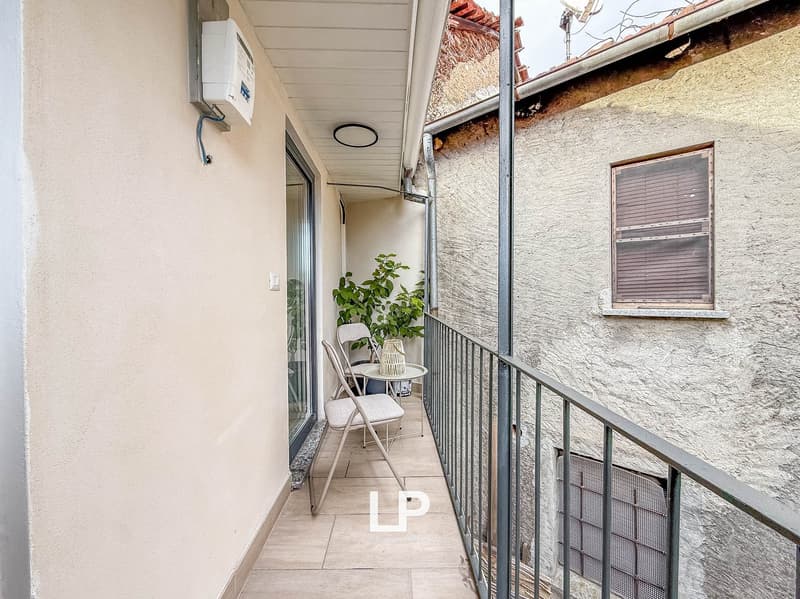 balcony with tiled flooring, metal railing, folding chairs, small table, potted plant, entrance with sliding glass door, power outlet and water meter