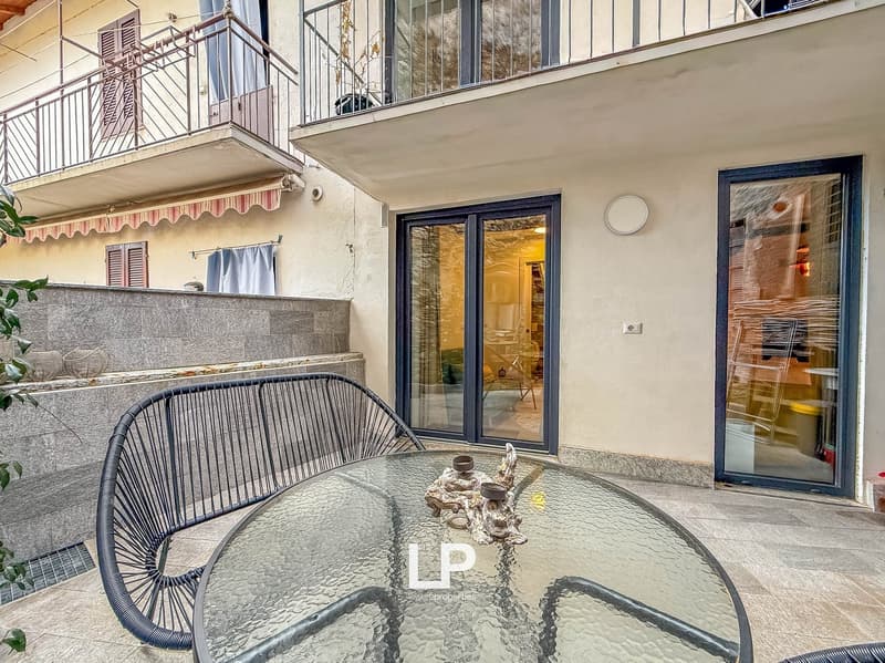 Terrace with round table and chairs, floor-to-ceiling glass doors, balconies above, outdoor views