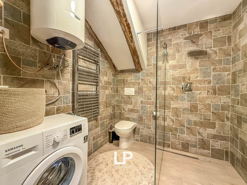 bathroom with shower, toilet, washing machine, towel rack, water heater