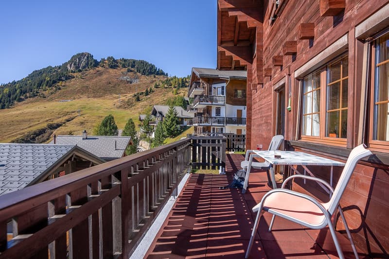 wooden railing balcony with table and chairs, wooden floor, surrounding views of mountainous landscape