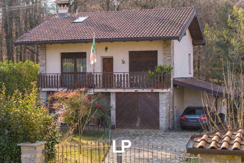 two-story house, brown roof, garage, car parked, balcony, surrounded by trees