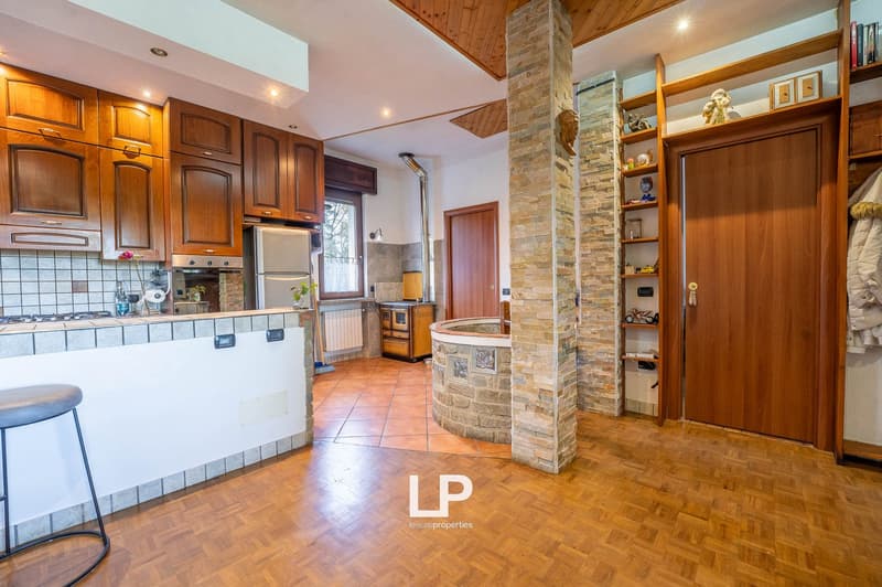 wooden cabinets, tiled floor, countertop with stove, refrigerator, and sink, open area with stove and round tub, wooden shelves, ceiling lamp