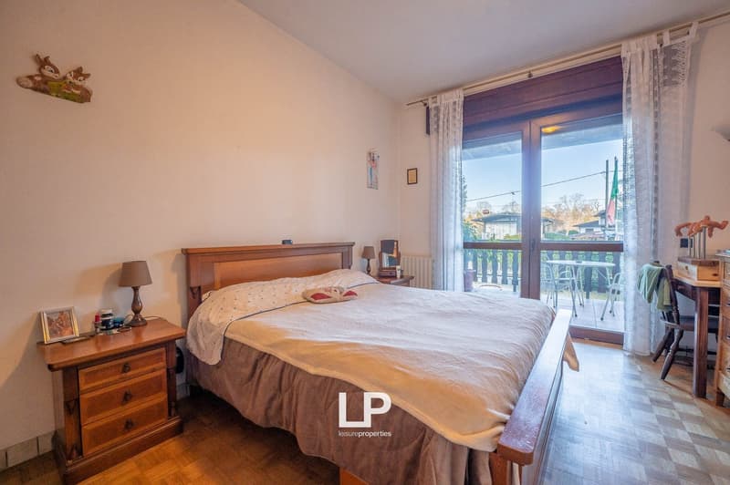 Queen bed, nightstand, desk, chair, balcony, sliding glass door, radiator, picture frames, lamp, decorative items