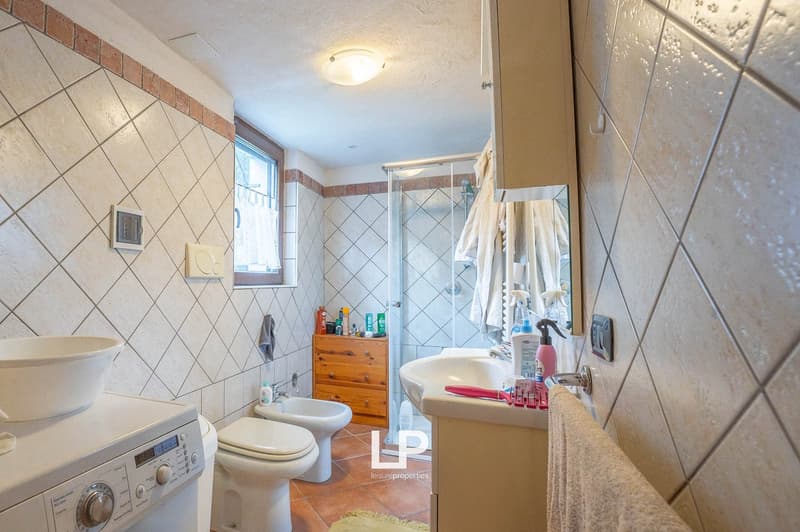 White ceramic tiles, white appliances, bidet, toilet, sink, shower, wooden storage box