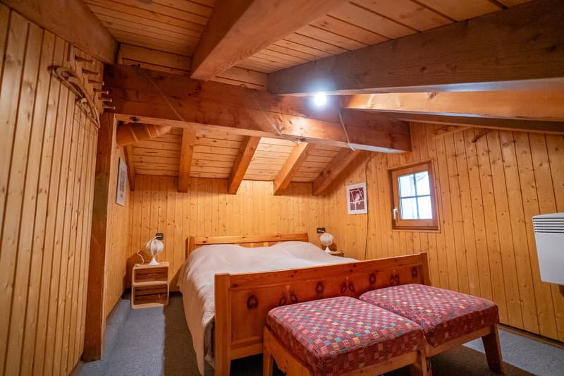 wood paneling walls, wooden bed, two ottomans, two nightstands, small window