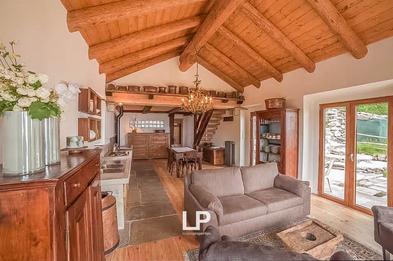 beamed ceiling, hardwood floors, open-plan living room, dining area, wooden table, chairs, couch, chandelier, wooden cabinet, flower vase, kitchen area with double sink