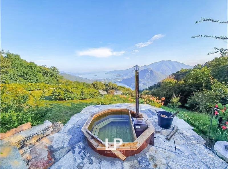 outdoor wooden hot tub, wooden fence, surrounding vegetation, bucket, stick