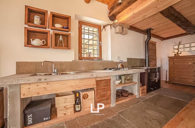 wooden countertops, wood cabinets, fireplace, large window, kettle, gas stove, sink with faucet, bottles, shelves