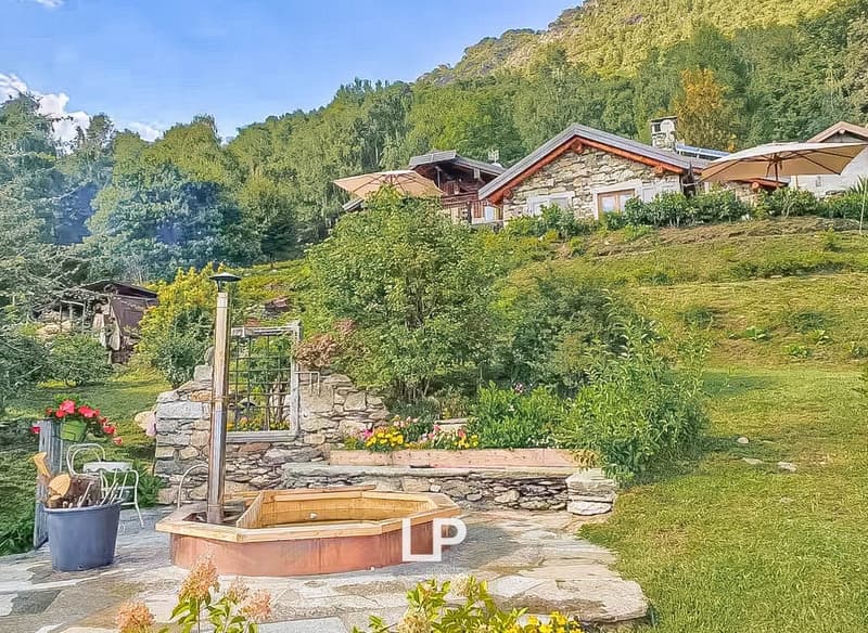 House built on slope, wooden exterior, garden, hot tub, mountain view, umbrellas