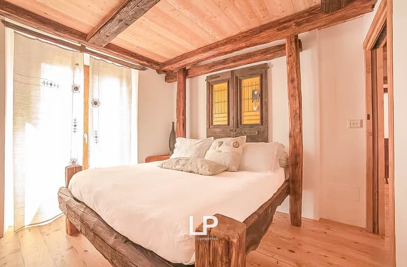wooden bed with pillows, wooden floor, curtains, nightstand