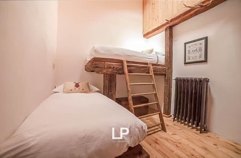 2 beds, wooden ladder, wooden floor, wall mounted radiator, picture frame on the wall