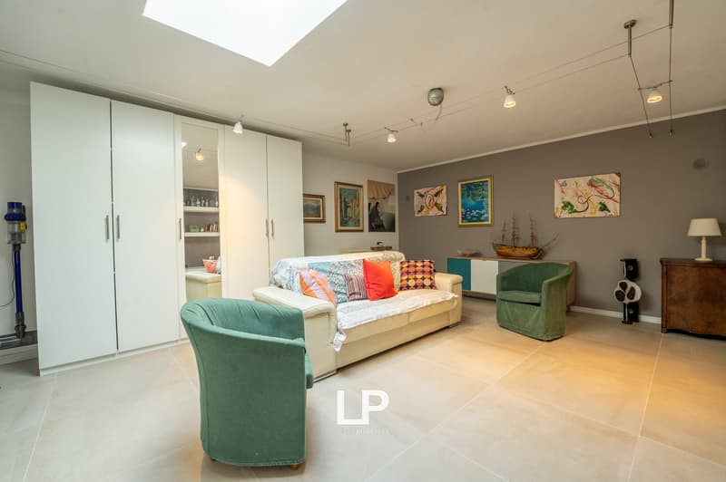 white couch, green chairs, cabinet, lamps, paintings, tiles
