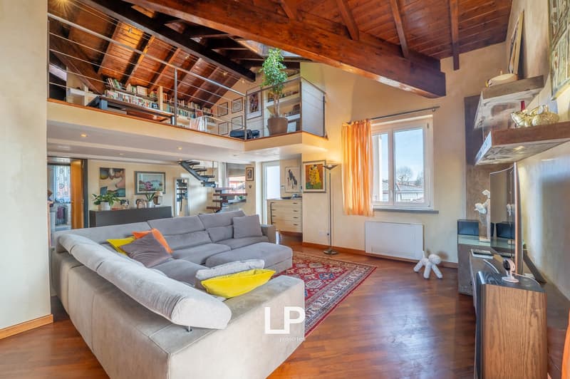 raised ground floor, hardwood floors, gray couch, oriental rug, wooden balcony, view of outside, high ceiling, wooden beam