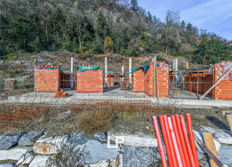 Building structure in progress, made of bricks, scaffolding and wire mesh in surrounding area, mountain in the background