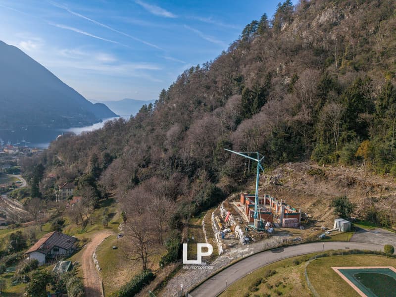 House under construction on a hill with trees, mountains, and a lake in the distance