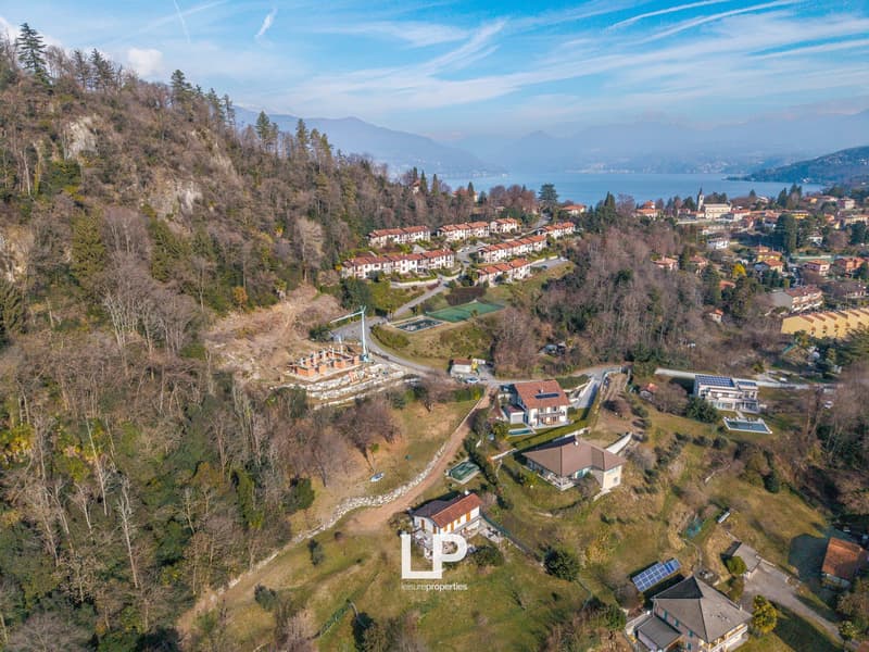 Hillside residential complex, multiple houses, visible mountains, large sea view, solar panels on rooftops