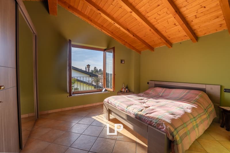 a bedroom with a bed, wooden ceiling, green wall, and a window with a balcony