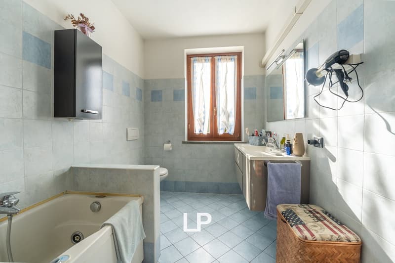 Bathroom with bathtub, sink, toilet, cabinet, towel, mirror, hairdryer and basket