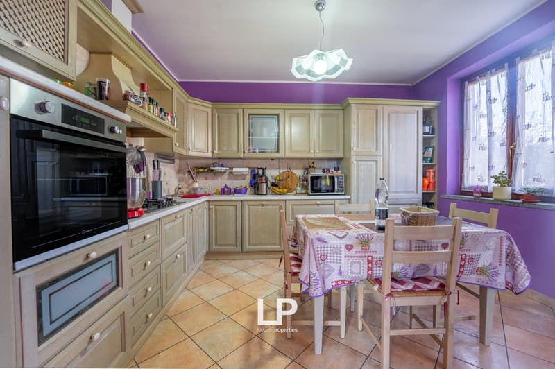 kitchen, wooden cabinets, tiled floor, microwave, refrigerator, large oven, dining area with table and chairs