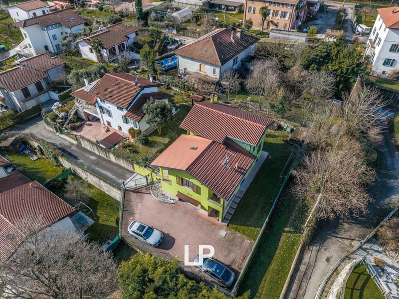 Three story house, green exterior, red roof, parking lot, garage, two cars parked