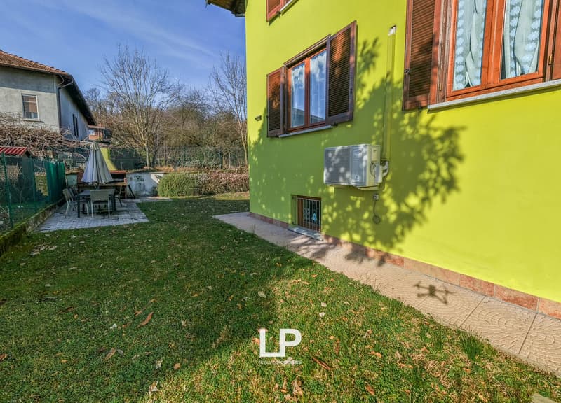 green lawn, table and chairs, yellow wall, windows, air conditioner unit