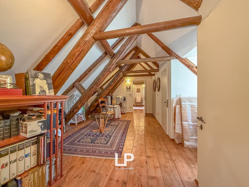 Wooden floor, exposed wooden beams, carpet, books, table, rug, chair, globe, picture frames