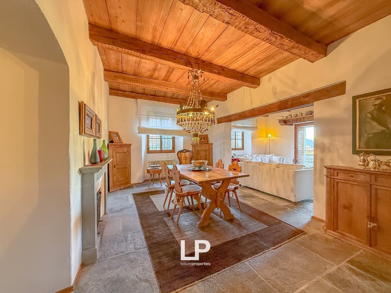 Wooden ceiling, chandelier, wooden table, fireplace, armchair, shelves, picture frames