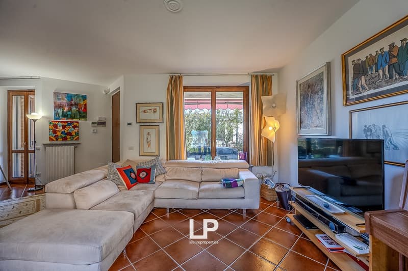 L-shaped couch, decorative pictures, radiator, floor lamp, flat screen TV, entertainment center, tiled flooring