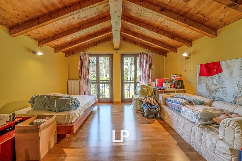 wooden floors, wooden ceiling beams, two beds, two windows with curtains, baby stroller, map, boxes