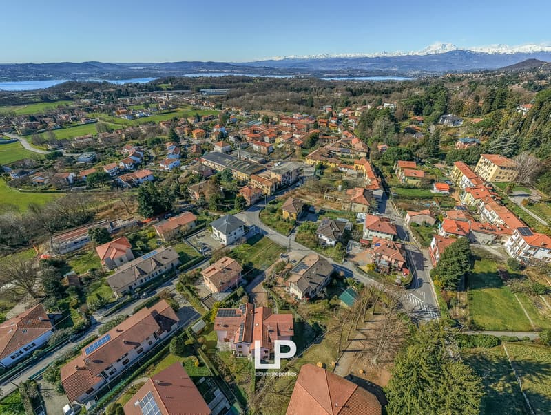 Overview of town with various houses, mountains in the distance, solar panels, lush greenery