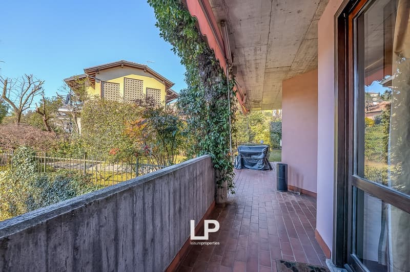 Terrace with brick flooring, covered by a canopy, plants, and covered barbecue area