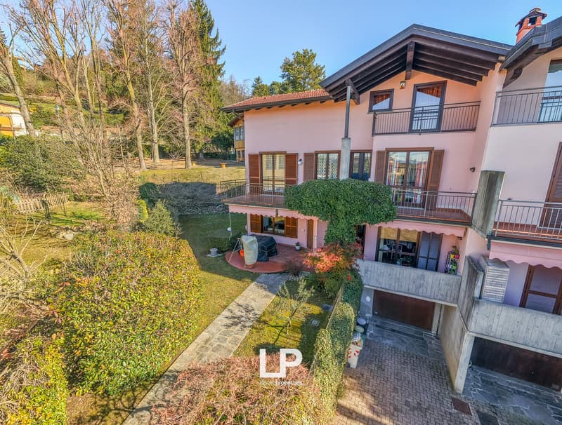 2 story house, pink walls, brown roof, balcony, garage, fenced yard, plants