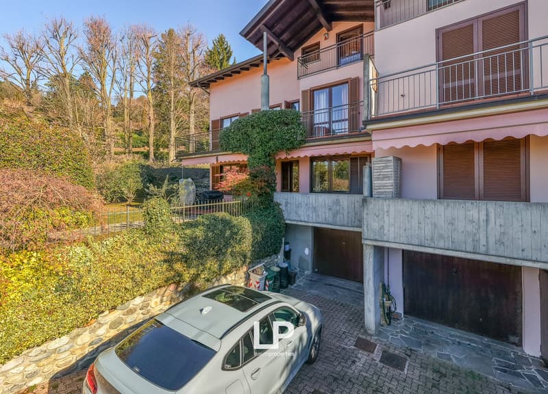 Two story house, beige walls, brown roof, balconies, garages, parked car
