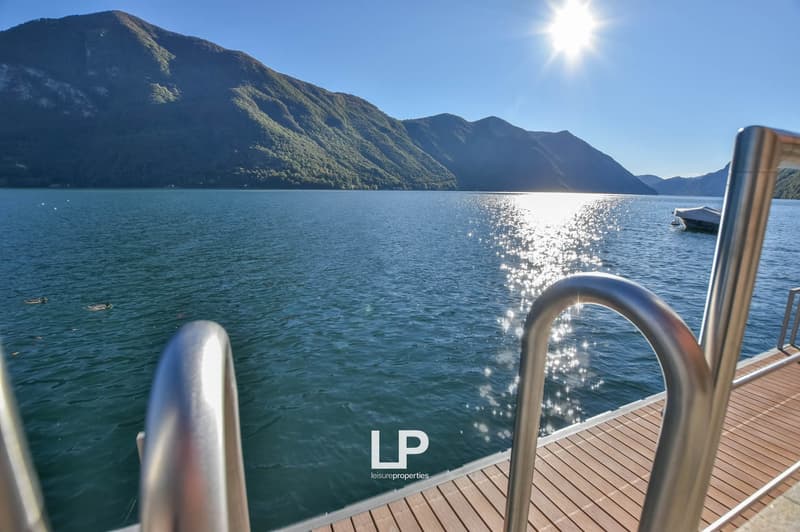 wooden dock, railings, water, mountains, sky