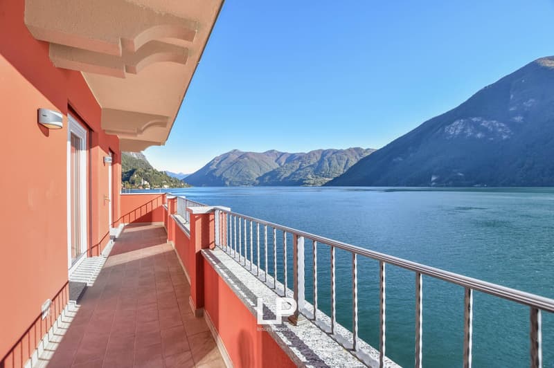 Exterior balcony with tiled floor, metal railing, access from a door, stunning lake view, mountains in the background