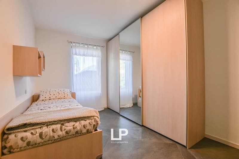 Single bed, wooden bed frame, white pillow, blanket, white curtains, wooden shelves, large mirror, wooden wardrobe